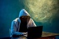 Hooded computer hacker stealing information with laptop Royalty Free Stock Photo