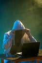 Hooded computer hacker stealing information with laptop Royalty Free Stock Photo