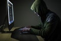 Hooded computer hacker stealing information with pc in Dark room background Royalty Free Stock Photo