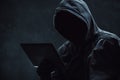 Hooded computer hacker using digital tablet