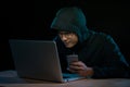 Hooded cyber crime hacker using mobile phone internet hacking in