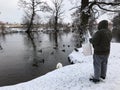 A hooded fat man feeding ducks and swans