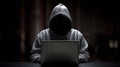 The hooded figure immersed in the glow of a laptop screen in darkness..AI generated image Royalty Free Stock Photo