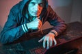 Hooded hacker is typing on a laptop keyboard in a dark room under a neon light. Cybercrime fraud and identity theft Royalty Free Stock Photo