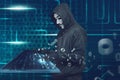 Hooded man with anonymous mask typing on virtual keyboard