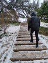 Hooded man climbing snowy stairs