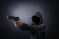 Hooded man with a gun in the dark Royalty Free Stock Photo