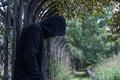 A hooded man, looking down, depressed and alone. standing next to a metal fence on a country path. signifying mental health issues Royalty Free Stock Photo