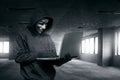 Hooded man with mask using laptop to hacking