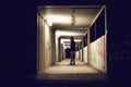 Hooded man standing in construction passage at night.