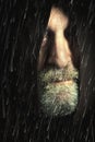 Hooded man tramp in the rain with sackcloth and beard, face partially hidden Royalty Free Stock Photo