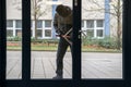 Hooded Man Using Crowbar To Open Glass Door Royalty Free Stock Photo