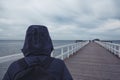 Hooded person on wooden pier walkway