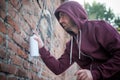 Hooded tagger writing graffiti on urban walls Royalty Free Stock Photo