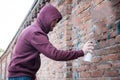 Hooded tagger writing graffiti on urban walls Royalty Free Stock Photo