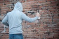 Hooded tagger writing graffiti on urban walls Royalty Free Stock Photo
