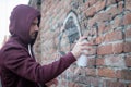 Hooded tagger writing graffiti on urban walls Royalty Free Stock Photo