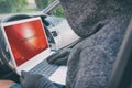Hooded thief tries to break the car`s security systems with laptop Royalty Free Stock Photo