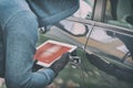 Hooded thief tries to break the car`s security systems with tablet Royalty Free Stock Photo