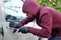 Hooded thief trying to open a car door lock