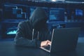 Hooded unknown hacker using laptop computer