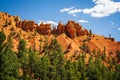 Red orange hoodoos standing guard in green forest against blue sky Royalty Free Stock Photo