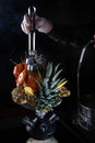 The hookah man lays the coals with tongs. Hookah on pineapples and oranges. Smoking device. The concept of smoking Royalty Free Stock Photo