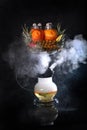 Hookah on pineapples and oranges. Smoking device. Hookah on a black background with a mixture of citrus and pineapple Royalty Free Stock Photo