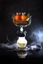 Hookah on pineapples and oranges. A smoking device. Hookah on a black background with a mixture of citrus and pineapple Royalty Free Stock Photo