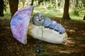 Caterpillar smoking hookah from Alice wonderland art object outdoor art exhibition in green forest