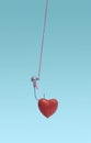 Catching love concept. Hooked red shiny heart hanging on pink thread on a blue background. Royalty Free Stock Photo