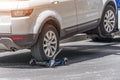 Hooked up car on a tow truck on a roadside, close up view of the rear wheel of a car and a transportation platform Royalty Free Stock Photo