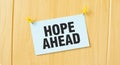 HOPE AHEAD sign written on sticky note pinned on wooden wall