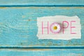 Hope, handwritten word on lined paper with flower on blue wooden table, top view