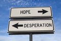 White two street signs with arrow on metal pole with word hope and desperation