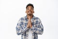 Hopeful african american man praying god, holding hands in begging supplication gesture, looking up in sky, beg Lord