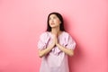 Hopeful asian girl praying god, looking up to plead or pray, making wish, supplicating with dramatic face, standing Royalty Free Stock Photo