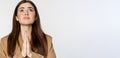 Hopeful corporate woman, student praying, begging god, looking up and pleading, standing over white background Royalty Free Stock Photo