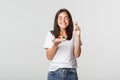 Hopeful and happy smiling birthday girl cross fingers and making wish while blowing candle on b-day cake Royalty Free Stock Photo