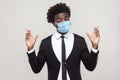 Hopeful or wishful. Portrait of worry young handsome worker man in black suit with surgical medical mask standing with crossed