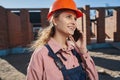 Hopeful young lady in builder uniform chatting on the phone Royalty Free Stock Photo