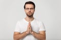 Hopeful young man in glasses praying to God.