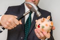 Hopeless businessman breaking piggy bank with hammer Royalty Free Stock Photo
