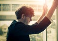 Hopeless Businessman looking out windows with worrying face standing