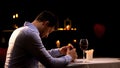 Hopeless man holding engagement ring, sitting in restaurant alone, break up Royalty Free Stock Photo