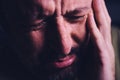 Hopelessness and despair, closeup of portrait of sad crying adult man grieving in dark room Royalty Free Stock Photo