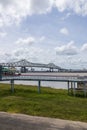 The Horace Wilkinson Bridge over the flowing waters off the Mississippi River with boats on the water, lush green grass and clouds Royalty Free Stock Photo