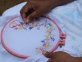 Side view of an Asian woman sewing a hand embroidery of colorful flowers with leaves