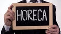 HoReCa written on blackboard in businessman hands, catering service industry