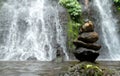 Horisontal shot of rocks perfectly balanced on top of each other in front of a waterfall in a forest Royalty Free Stock Photo